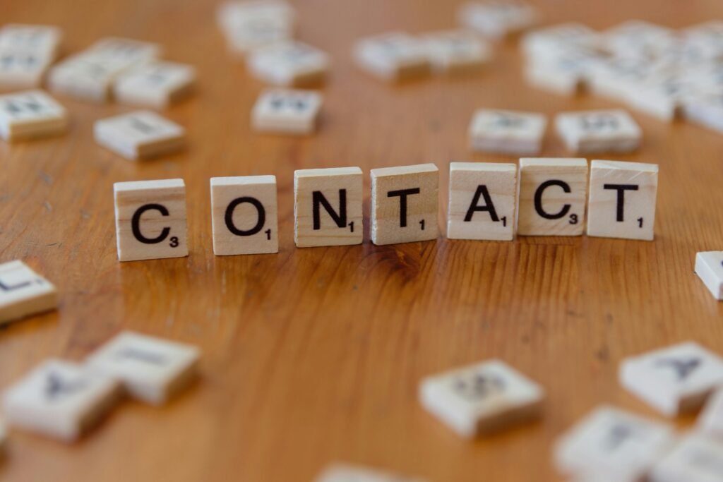LIÊN HỆ Scrabble letters spelling 'contact' on a wooden table surface.